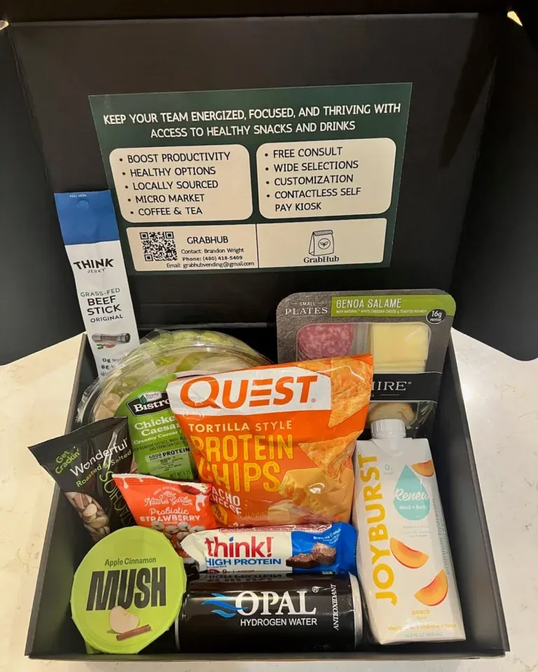 A black gift box filled with assorted healthy snacks, protein bars, chips, dried fruit, a beef stick, apple cinnamon mush, hydrating water, and info about workplace wellness services—perfect for Phoenix offices or self checkout kiosk setups.